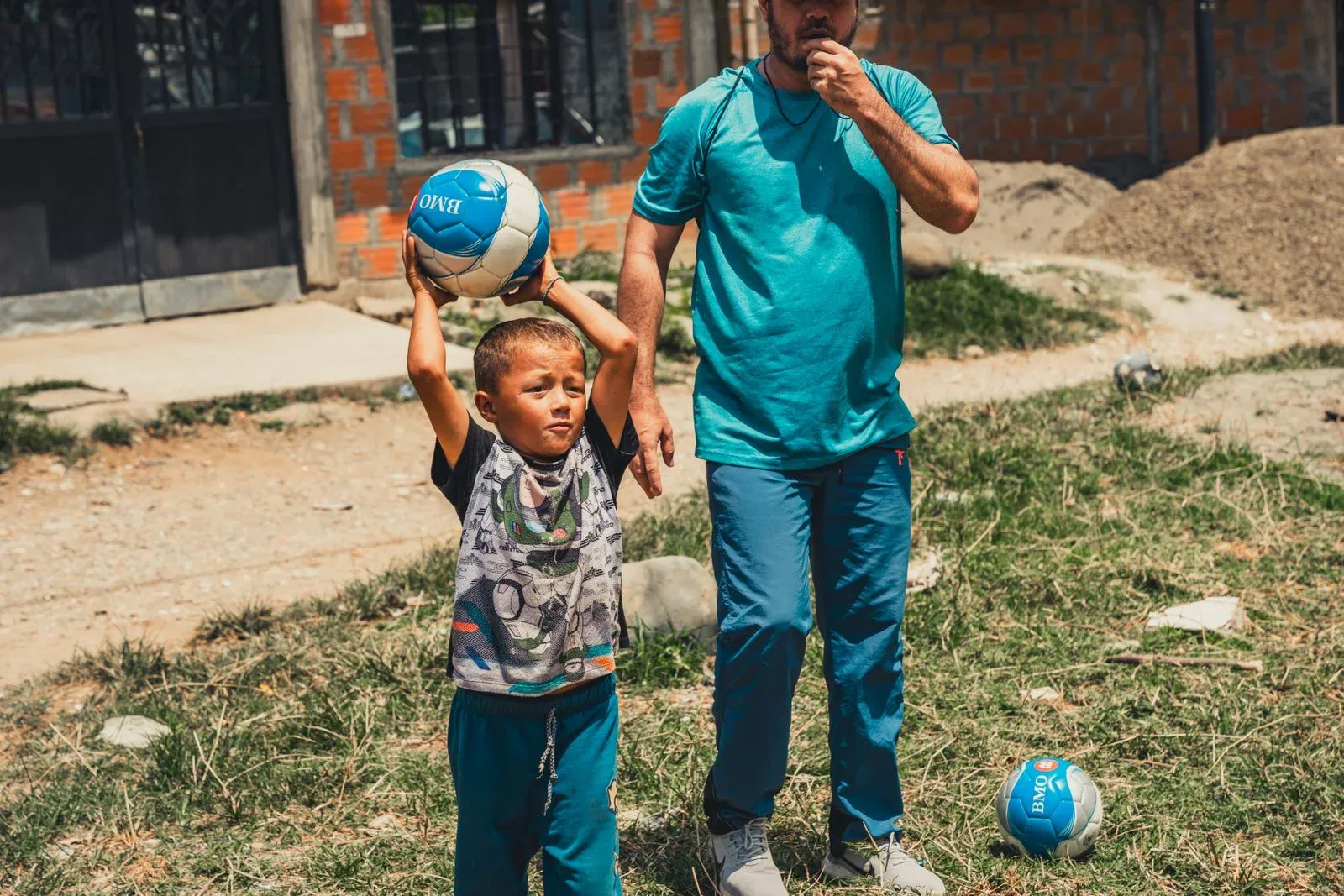 Parent and child playing with a soccer ball outdoors
