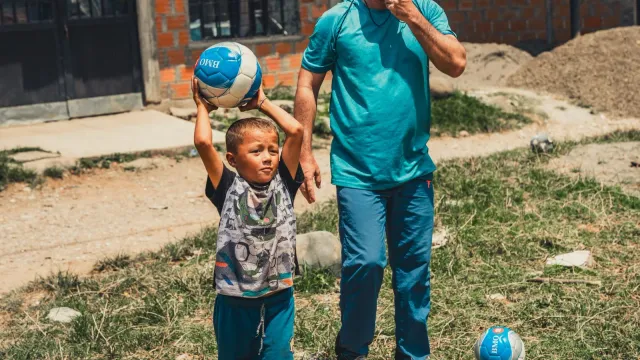 Parent and child playing with a soccer ball outdoors