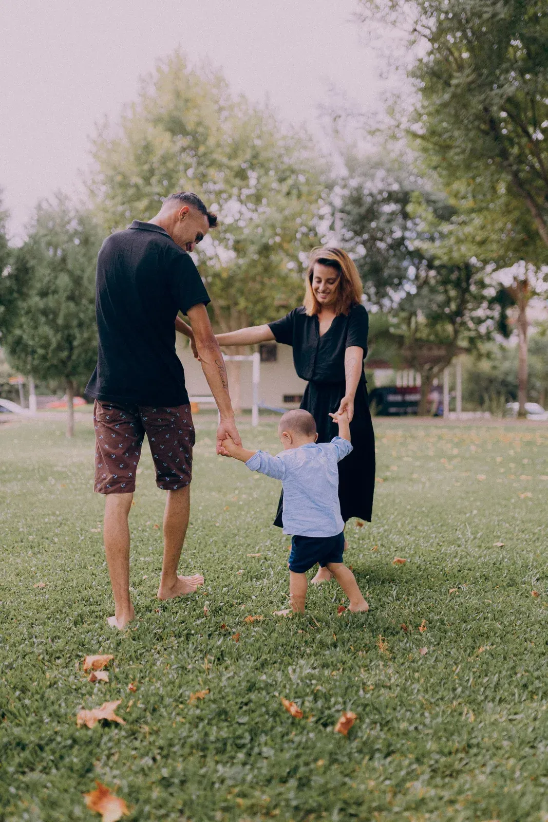 Parents playing with a toddler in a sunny park