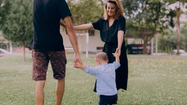 Parents playing with a toddler in a sunny park