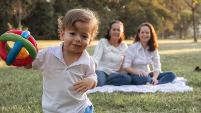 Family relaxing on a picnic blanket with a toddler in a sunny park