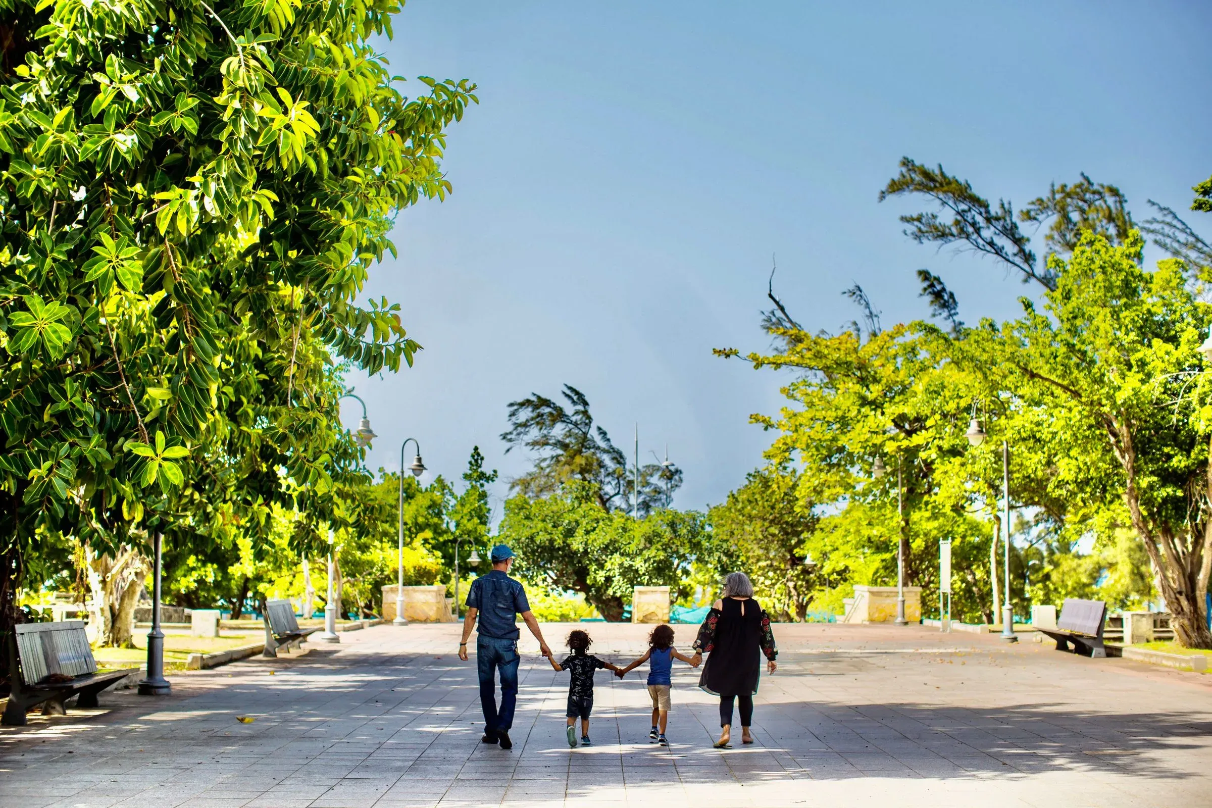 Family walking together through a sunny park plaza