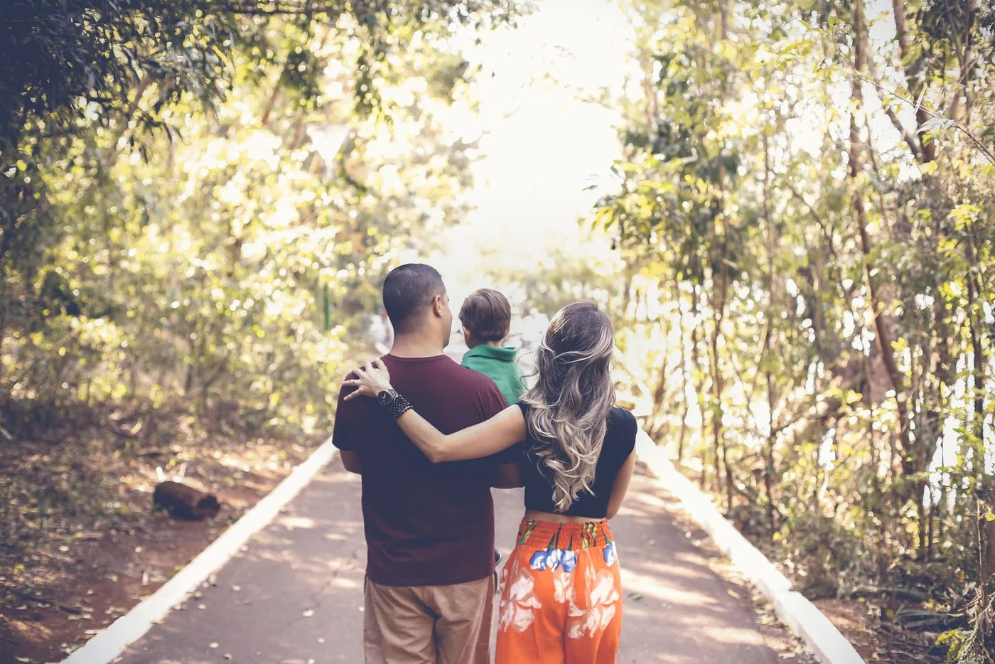 Family walking together along a tree-lined park path